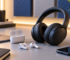 Wireless earbuds and over-ear headphones on a clean desk with a phone and audio accessories